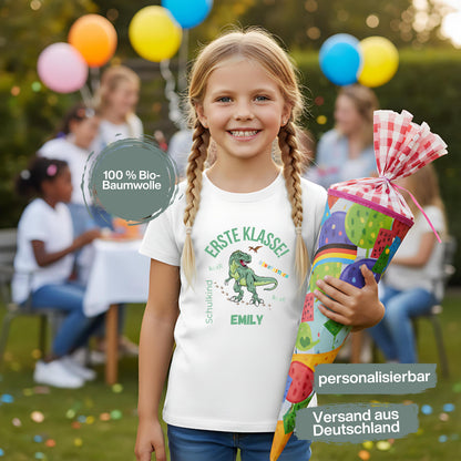 Personalisiertes Schulkind T-Shirt 2026 mit grünem Dinosaurier-Motiv und Spruch „Erste Klasse – Dinotastisch!“. Einschulungsshirt mit Name oder ohne, ideal als Geschenk zur Einschulung, für Kita Abschied, Einschulungsfeier oder ersten Schultag. T-Shirt Schulkind für Jungen und Mädchen, geeignet als Erstklässler T-Shirt, Tschüss Kindergarten Shirt, Schulkind Outfit oder Schulanfang Geschenk. Einschulung T-Shirt für Dinofans – stark, liebevoll, hochwertig und perfekt für den Schulstart 2026.