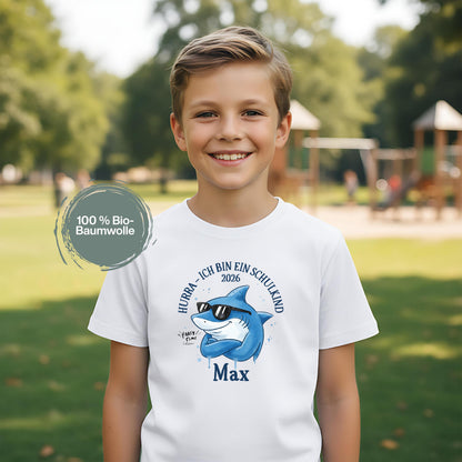 Cooles Schulkind T-Shirt 2026 mit Hai-Motiv, perfekt für Jungen zur Einschulung. Ideal als Geschenk zum Schulanfang für mutige Kinder, die mit Stil in die 1. Klasse starten. Das T-Shirt zur Einschulung besteht aus 100 % Bio-Baumwolle und kann mit Namen personalisiert werden. Perfekt als Einschulung Shirt Junge, T-Shirt endlich Schulkind, Geschenk Einschulung Kind, T-Shirt für Erstklässler oder Bye Bye Kindergarten Geschenk. Dieses Einschulungsshirt bringt und Vorfreude auf den Schulstart