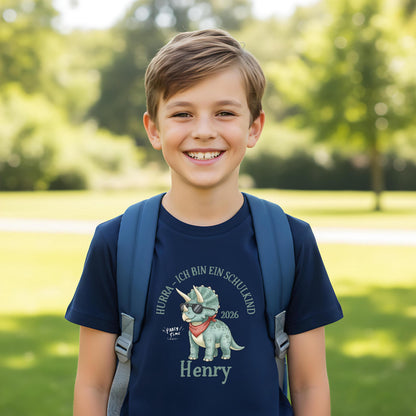 T-Shirt zur Einschulung 2026 mit Dino-Motiv – perfekt für Jungen, die stolz Schulkind werden. Personalisiertes Schulkind T-Shirt mit Name, ideal als Geschenk zur Einschulung oder für die Schultüte. Triceratops mit Sonnenbrille und Halstuch sorgt für Spaß und Selbstbewusstsein beim Schulstart. Hochwertiges Einschulung Shirt Junge aus 100 % Bio-Baumwolle, bequem und robust. Ein liebevolles, witziges T-Shirt für Erstklässler und ein ideales Bye Bye Kindergarten Abschiedsgeschenk.