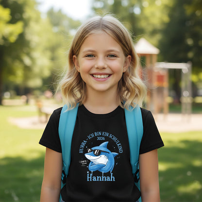 Cooles Schulkind T-Shirt 2026 mit Hai-Motiv, perfekt für Jungen zur Einschulung. Ideal als Geschenk zum Schulanfang für mutige Kinder, die mit Stil in die 1. Klasse starten. Das T-Shirt zur Einschulung besteht aus 100 % Bio-Baumwolle und kann mit Namen personalisiert werden. Perfekt als Einschulung Shirt Junge, T-Shirt endlich Schulkind, Geschenk Einschulung Kind, T-Shirt für Erstklässler oder Bye Bye Kindergarten Geschenk. Dieses Einschulungsshirt bringt und Vorfreude auf den Schulstart