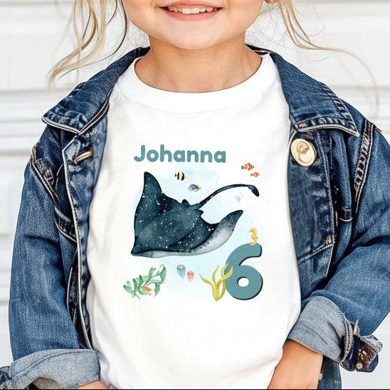 Personalisiertes Geburtstagsshirt für Kinder mit großem Rochen, tropischen Fischen, Algen, Name und Geburtstagszahl. Individuelles Kindergeburtstags-Outfit für Mädchen und Jungen mit Unterwasser-Motiv und Meerestiere-Design. Perfekt als Geburtstags-T-Shirt mit Namen, persönliches Geburtstagsgeschenk für Kinder oder Outfit für Meerjungfrauen-Party, Unterwasserparty oder Ozean-Geburtstag. Personalisierbares Kinder-Shirt mit Rochen, Zahl und Namen. T-Shirt zum Geburtstag für kleine Meeresfans und Ozean-Liebhab