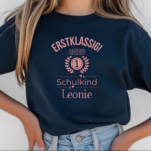 Personalisiertes Schulkind T-Shirt 2026 für Mädchen mit rosa Motiv „Erstklassig“, Einschulungsshirt mit Name, Bio-Baumwolle, perfekt als Geschenk zum Schulanfang 2026. Schulkind Shirt 1. Klasse, T-Shirt zur Einschulung, Zuckertüte Geschenk Mädchen, Erstklässler T-Shirt mit Jahreszahl, Lorbeerkranz und Zahl 1. Ideal als Einschulungsgeschenk, Abschied Kindergarten, Schulkind Outfit 2026 für Mädchen, T-Shirt Einschulungsfeier, Schulstart Kleidung mit Namen Erstklassig Schulkind T-Shirt 2026 Mädchen
