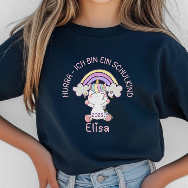 Schulkind T-Shirt 2026 mit Regenbogen und süßem Einhorn-Motiv – personalisierbar mit Namen. Perfekt als Einschulungsgeschenk für Mädchen zum Schulstart. Ideal für den ersten Schultag, Einschulungsfeier oder als Outfit für das Klassenfoto. Hochwertig bedruckt auf weicher Bio-Baumwolle, mit dem Spruch „Hurra – ich bin ein Schulkind“. Ein liebevoll gestaltetes T-Shirt zur Einschulung, das Magie, Mut und Vorfreude ausstrahlt. Geschenkidee für Schulanfängerinnen mit Herz und Fantasie.