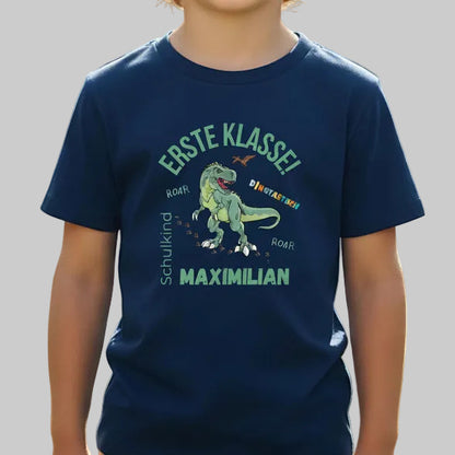 Personalisiertes Schulkind T-Shirt 2026 mit grünem Dinosaurier-Motiv und Spruch „Erste Klasse – Dinotastisch!“. Einschulungsshirt mit Name oder ohne, ideal als Geschenk zur Einschulung, für Kita Abschied, Einschulungsfeier oder ersten Schultag. T-Shirt Schulkind für Jungen und Mädchen, geeignet als Erstklässler T-Shirt, Tschüss Kindergarten Shirt, Schulkind Outfit oder Schulanfang Geschenk. Einschulung T-Shirt für Dinofans – stark, liebevoll, hochwertig und perfekt für den Schulstart 2026.
