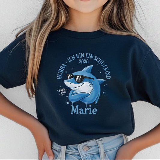 Cooles Schulkind T-Shirt 2026 mit Hai-Motiv, perfekt für Jungen zur Einschulung. Ideal als Geschenk zum Schulanfang für mutige Kinder, die mit Stil in die 1. Klasse starten. Das T-Shirt zur Einschulung besteht aus 100 % Bio-Baumwolle und kann mit Namen personalisiert werden. Perfekt als Einschulung Shirt Junge, T-Shirt endlich Schulkind, Geschenk Einschulung Kind, T-Shirt für Erstklässler oder Bye Bye Kindergarten Geschenk. Dieses Einschulungsshirt bringt und Vorfreude auf den Schulstart