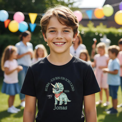 T-Shirt zur Einschulung 2026 mit Dino-Motiv – perfekt für Jungen, die stolz Schulkind werden. Personalisiertes Schulkind T-Shirt mit Name, ideal als Geschenk zur Einschulung oder für die Schultüte. Triceratops mit Sonnenbrille und Halstuch sorgt für Spaß und Selbstbewusstsein beim Schulstart. Hochwertiges Einschulung Shirt Junge aus 100 % Bio-Baumwolle, bequem und robust. Ein liebevolles, witziges T-Shirt für Erstklässler und ein ideales Bye Bye Kindergarten Abschiedsgeschenk.
