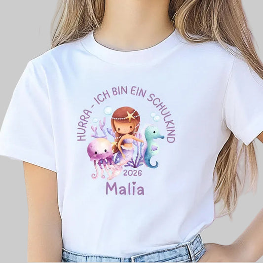 Personalisiertes Schulkind T-Shirt 2026 mit Meerjungfrau-Motiv – liebevoll gestaltetes Einschulungsshirt für Kinder, ideal für Mädchen, die den Ozean und Fantasiewelten lieben. Perfekt als Geschenk zur Einschulung, zur Einschulungsfeier oder für das erste Klassenfoto. Weiches Bio-Baumwoll-Shirt mit personalisierbarem Namen, bequem und hochwertig verarbeitet. Schulkind Outfit 2026 mit Unterwasser-Prinzessin – märchenhaft, mutig und bereit für die 1. Klasse. T-Shirt Schulkind Meerjungfrau