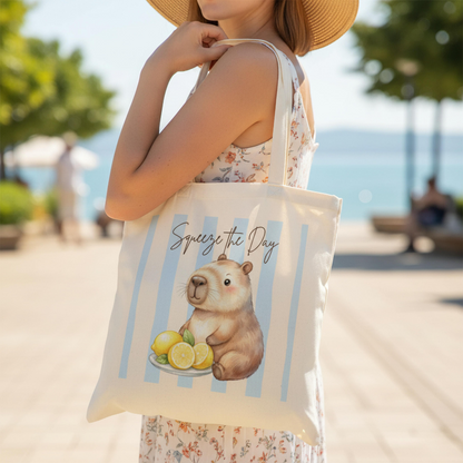 Capybara Stofftasche aus hochwertiger Baumwolle mit niedlichem Capybara und frischen Zitronen im sommerlichen Streifen-Design. Der Stoffbeutel zeigt den Spruch „Squeeze the Day“ und eignet sich als Einkaufstasche, Tragetasche oder Baumwolltasche für Alltag, Shopping, Urlaub und Freizeit. Perfekt als Capybara Tasche, Capybara Geschenk oder Geschenk für Capybara Fans und Tierliebhaber. Robuster Stoffbeutel mit hochwertigem Druck, langen Henkeln und Sommermotiv, ideal als nachhaltige Einkaufstasche