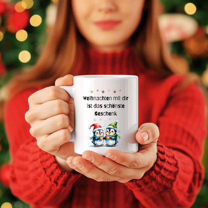 Weihnachtstasse mit Spruch „Weihnachten mit dir ist das schönste Geschenk“ als originelle Geschenkidee für Freundin, Partnerin, Kollegin oder Ehefrau. Die Kaffeetasse zeigt zwei niedliche Pinguine mit Weihnachtsmütze, die Kakao halten – perfekt für Winter, Advent und Weihnachtszeit. Lustige Tasse Weihnachten für Paare, Familien, Büro oder Zuhause. Hochwertiger Keramikbecher, ideal als kleines Geschenk, Wichtelgeschenk oder Weihnachtsgeschenk für Frauen, Pinguin-Fans, Kollegen, Kaffeeliebhaber.