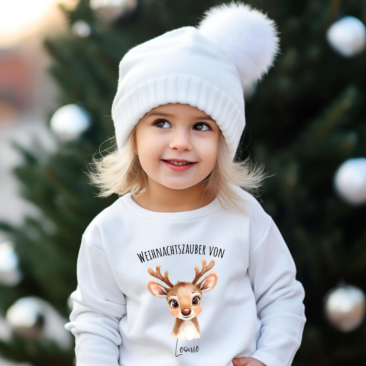 Weihnachtspullover mit niedlichem Rentier-Motiv und dem Text „Weihnachtszauber von [Name]“ – personalisierbar und ideal als Weihnachtsoutfit für Kinder. Perfekt für Jungen, Mädchen oder Babys als festlicher Pullover, Weihnachts-T-Shirt oder Babybody. Der süße Rentier-Print mit Geweih und großen Augen macht das Design zum Hingucker auf Weihnachtsfotos, bei der Bescherung oder im Partnerlook mit Geschwistern. Eine liebevolle Geschenkidee für die Feiertage mit persönlichem Namen.
