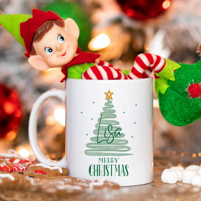 Personalisierbare Weihnachtstasse mit modernem Tannenbaum-Design in Mintgrün, verziert mit einem goldenen Stern und dem Schriftzug "Merry Christmas" – darunter individualisierbar mit Wunschnamen wie Felix oder Laura. Die Keramiktasse ist ein Geschenk zu Weihnachten für Freunde, Kinder, Partner oder Familie. Ideal als individuelles Weihnachtsgeschenk, Wichtelgeschenk oder festliche Wintertasse mit Namen – perfekt für die Adventszeit, Heiligabend oder als besondere Überraschung im Nikola
