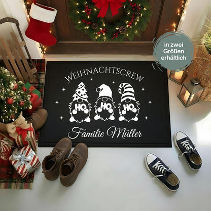 Personalisierte Fußmatte mit Weihnachtsdesign „Weihnachtscrew“ – drei Gnome mit HO HO HO-Motiven und Wunschname der Familie darunter. Diese schwarze Weihnachtsfußmatte ist rutschfest, wetterbeständig und ideal als individuelle Fußmatte für den Eingangsbereich zu Weihnachten. Perfekt als Geschenkidee für Familien, als Weihnachts-Willkommensmatte oder Türmatte mit Namen. Ein festlicher Blickfang für alle, die Weihnachten lieben und den Eingangsbereich dekorativ und persönlich gestalten wollen.