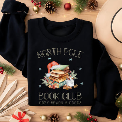 Weihnachtspullover für Damen mit Bücherstapel, Weihnachtsmütze und Kakao – perfektes Winter-Outfit für Leseratten und Buchliebhaberinnen. Der Sweater zeigt das Motiv „North Pole Book Club – Cozy Reads & Cocoa“ und verbindet Weihnachtsfreude mit Leseleidenschaft. Ideal als Geschenk zu Weihnachten oder Nikolaus für Frauen, die Bücher lieben. Ein kuscheliges, winterliches Oberteil für gemütliche Lesestunden, Weihnachtsfeiern oder den Advent. ein süßer Hingucker für die festliche Saison!
