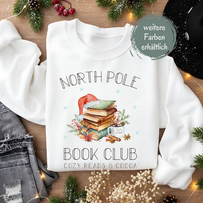 Weihnachtspullover für Damen mit Bücherstapel, Weihnachtsmütze und Kakao – perfektes Winter-Outfit für Leseratten und Buchliebhaberinnen. Der Sweater zeigt das Motiv „North Pole Book Club – Cozy Reads & Cocoa“ und verbindet Weihnachtsfreude mit Leseleidenschaft. Ideal als Geschenk zu Weihnachten oder Nikolaus für Frauen, die Bücher lieben. Ein kuscheliges, winterliches Oberteil für gemütliche Lesestunden, Weihnachtsfeiern oder den Advent. ein süßer Hingucker für die festliche Saison!