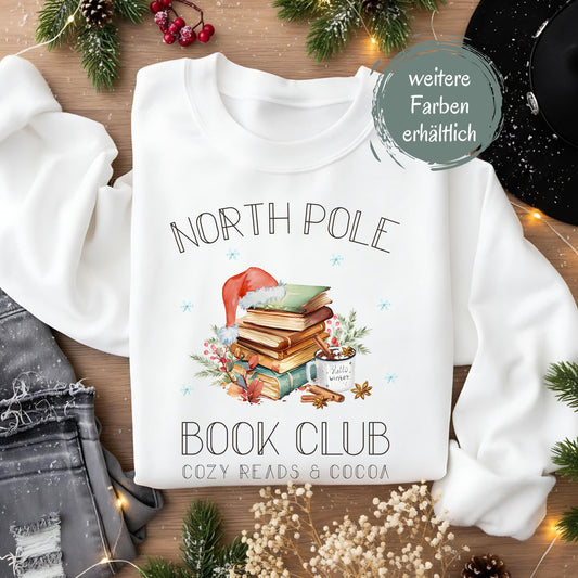Weihnachtspullover für Damen mit Bücherstapel, Weihnachtsmütze und Kakao – perfektes Winter-Outfit für Leseratten und Buchliebhaberinnen. Der Sweater zeigt das Motiv „North Pole Book Club – Cozy Reads & Cocoa“ und verbindet Weihnachtsfreude mit Leseleidenschaft. Ideal als Geschenk zu Weihnachten oder Nikolaus für Frauen, die Bücher lieben. Ein kuscheliges, winterliches Oberteil für gemütliche Lesestunden, Weihnachtsfeiern oder den Advent. ein süßer Hingucker für die festliche Saison!