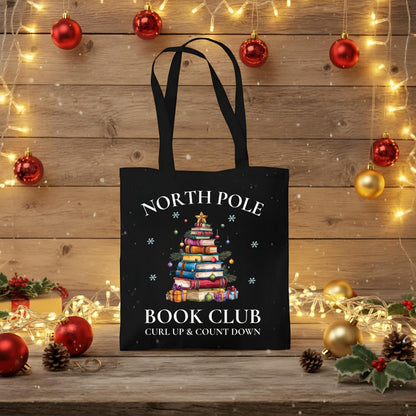 Baumwoll-Stofftasche mit weihnachtlichem Motiv: Ein Bücherbaum mit Stern und Geschenken symbolisiert den „North Pole Book Club“. Perfekt als Jutebeutel Weihnachten für Leseratten, Bücherfreunde, Bibliophile oder Buchclub-Mitglieder. Ideales Geschenk für Buchliebhaber und als nachhaltige Geschenkverpackung mit Buchthema zur Adventszeit. Baumwolltasche für Weihnachten & Buchfans. WeihnachtsStofftasche für Bücherfreunde! Der Jutebeutel ist das perfekte Geschenk für Buchliebhaber zur Adventszeit.