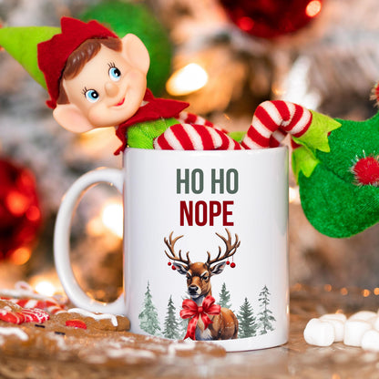 Lustige Anti-Weihnachtstasse mit Spruch „HO HO NOPE“ und Rentier-Motiv mit roter Schleife, Wald und Schnee. Weihnachtsbecher mit Humor, ideal als Geschenk Weihnachten für Kollegin, Freund, Freundin oder Familie. Perfekt als Wichtelgeschenk, Nikolausgeschenk oder kleines Geschenk für Weihnachtsmuffel. Hochwertige Keramiktasse mit Druck, beidseitig bedruckt. Geschenkidee Weihnachten mit Witz für Männer und Frauen. Statement-Tasse mit Weihnachtsspruch. Ideal für Büro Weihnachtsfeier