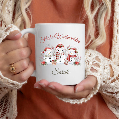 Personalisierte Weihnachtstasse mit winterlichem Schneemann-Motiv, bestehend aus drei festlich geschmückten Schneemännern mit Mütze und Schal sowie dem Schriftzug „Frohe Weihnachten“. Darunter ist der Wunschname – z. B. Sarah – elegant integriert. Diese Keramiktasse eignet sich ideal als individuelles Weihnachtsgeschenk für Freunde, Partner, Kinder oder Familie. Perfekt als Wichtelgeschenk, Nikolausidee oder festlicher Winterbecher für den Advent. Mit liebevollem Design und persönlicher Note.