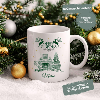 Weiße Keramiktasse mit festlichem Weihnachtsmotiv: Kamin mit festlich geschmücktem Weihnachtsbaum, Geschenken und einem eleganten Sessel. Darüber steht "Merry Christmas", begleitet von Rentier-Silhouetten. Unten ist ein Name personalisiert – in diesem Beispiel "Marie". Ideal als personalisiertes Weihnachtsgeschenk für Freund, Freundin, Partner oder Familienmitglied. Perfekt als Tasse für die Adventszeit, Nikolaus, Wichtelgeschenk oder als dekoratives Lieblingsstück für gemütl