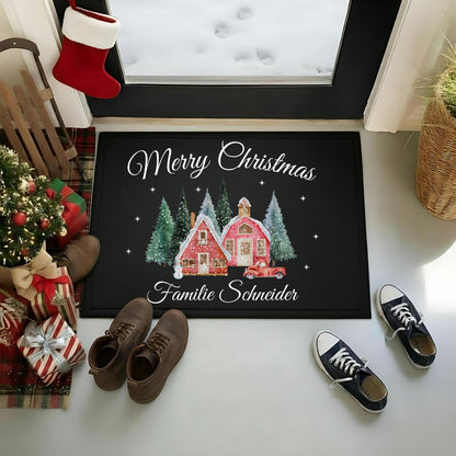 Personalisierte Weihnachtsfußmatte „Merry Christmas – Familie Schneider“ im Eingangsbereich vor einer Glastür mit Schnee dahinter. Zwei rote Winterhäuser, schneebedeckte Tannen, Sterne und ein rotes Auto schmücken die schwarze Matte. Schuhe, Weihnachtsgeschenke, kleiner Tannenbaum, Schlitten und roter Weihnachtsstrumpf ergänzen die Szene. Die rechteckige Türmatte mit Gummirand und Oberfläche aus 100 % Polypropylen gibt es in 40 × 60 oder 50 × 70 cm. Weihnachtsgeschenk mit Wunschname für Familie oder Paare.