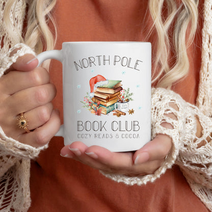 Weihnachtstasse „North Pole Book Club“ mit winterlichem Bücher-Motiv – perfektes Geschenk für Buchliebhaber, Leseratten und Weihnachtsfans. Die Tasse zeigt einen festlich dekorierten Bücherstapel mit Weihnachtsmütze, umgeben von winterlichen Elementen. Ideal als Geschenkidee zu Weihnachten für Vielleser, Buchclub-Mitglieder, Literaturfreunde, Kolleginnen oder Lehrerinnen. Ein liebevolles Präsent für Advent, Nikolaus oder Heiligabend – für gemütliche Lesemomente mit Kakao, Tee oder Kaffee