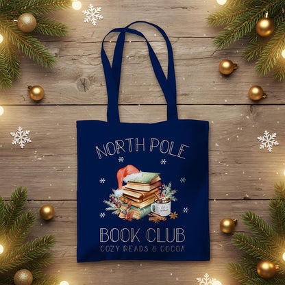 Baumwoll‑Jutebeutel mit weihnachtlichem Bücherbaum‑Motiv und Schriftzug „North Pole Book Club“. Ideal als Stofftasche Weihnachten für Leseratten, Buchliebhaber und Bibliophile – passend als Geschenk oder Einkaufstasche in der Advents‑ und Winterzeit. Hochwertige Baumwolltasche, langlebiger Druck, lange Henkel, umweltfreundlich und vielseitig nutzbar. Perfekt als Weihnachts‑Geschenktasche, Bücherbeutel oder nachhaltige Tasche mit Weihnachtsmotiv für Freunde, Familie oder für dich selbst.