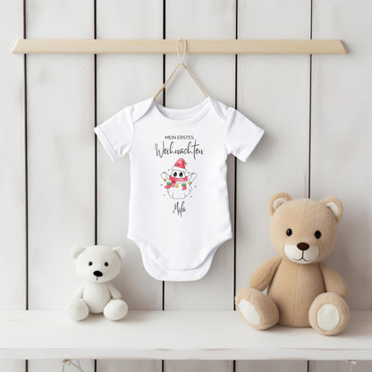 Babybody Weihnachten 2025 aus weißer Bio-Baumwolle mit rosa Weihnachtsgeist-Motiv, Nikolausmütze, buntem Schal und Sternen. Text „Mein erstes Weihnachten“ über dem Motiv, Name des Babys darunter personalisiert (z. B. Matteo). In Langarm oder Kurzarm wählbar. Ideal als Babybody personalisiert, Weihnachtsoutfit Baby, Geschenk zur Geburt oder Taufe im Winter. Hautfreundlich langlebiger Druck. Perfekt für Familienfotos, Partnerlook mit Geschwistern oder als festliche Babykleidung zur Weihnachtszeit.