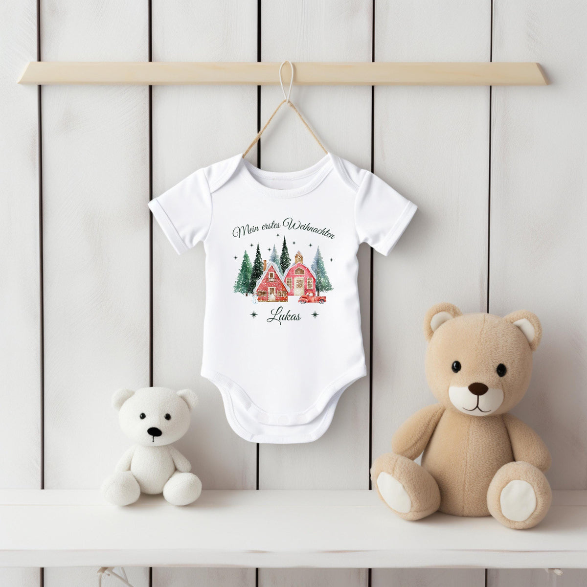 Babybody „Mein erstes Weihnachten“ mit nostalgischem Weihnachtsdorf-Motiv: zwei rote Häuser, verschneite Tannen und ein Vintage-Auto mit Weihnachtsbaum. Inklusive personalisiertem Namen (z. B. Luisa) unter dem Design. Aus 100 % Bio-Baumwolle, in Kurzarm oder Langarm erhältlich. Ideal als Geschenk zur Wintergeburt oder fürs erste Weihnachtsfest. Perfekt für Erinnerungsfotos, Familienfeiern oder Partnerlook mit Mama und Papa. Zauberhaftes Baby-Outfit für Weihnachten 2025.