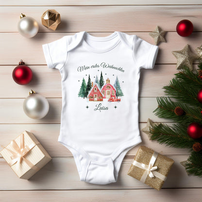 Babybody „Mein erstes Weihnachten“ mit nostalgischem Weihnachtsdorf-Motiv: zwei rote Häuser, verschneite Tannen und ein Vintage-Auto mit Weihnachtsbaum. Inklusive personalisiertem Namen (z. B. Luisa) unter dem Design. Aus 100 % Bio-Baumwolle, in Kurzarm oder Langarm erhältlich. Ideal als Geschenk zur Wintergeburt oder fürs erste Weihnachtsfest. Perfekt für Erinnerungsfotos, Familienfeiern oder Partnerlook mit Mama und Papa. Zauberhaftes Baby-Outfit für Weihnachten 2025.