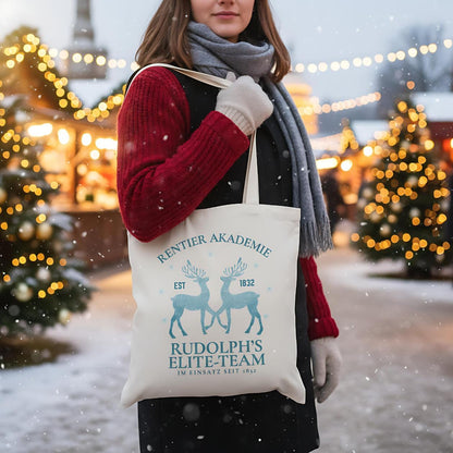 Weihnachtliche Stofftasche mit Rentier-Motiv „Rentier Akademie – Rudolph’s Elite-Team“ im Vintage-Stil. Ideale Baumwolltasche für Weihnachten, Einkäufe, Geschenke oder als nachhaltiger Jutebeutel. Perfekt als Geschenkidee oder als wiederverwendbare Geschenktasche mit Weihnachtsdesign. Waschbar, langlebig, mit langen Henkeln – als Weihnachtsgeschenktasche, Stoffbeutel oder Einkaufstasche nutzbar. Ideal für Damen, Herren oder Kinder zur Weihnachtszeit. Farben: Natur, Blau, Schwarz.