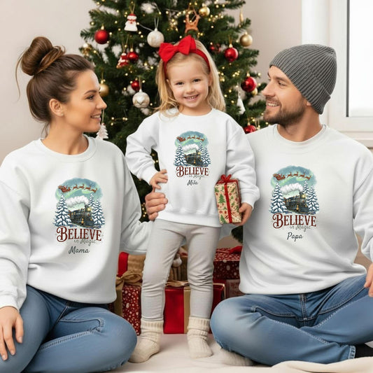 Personalisierter Weihnachtspullover mit nostalgischem Weihnachtszug und dem Spruch „Believe in Magic“ – ideal für Familien als Partnerlook Weihnachten. Das Motiv zeigt eine dampfende Lokomotive im verschneiten Wald, über ihr fliegt der Weihnachtsmann mit Rentieren durch den Nordlicht-Himmel. Für Kinder, Babys und Eltern als festliches Familienoutfit mit Namen. Perfekt für Weihnachtsfotos, Geschwisterpullover, Winterfeste oder als Geschenk für Mama, Papa, Oma, Opa & kleine Eisenbahn-Fans.