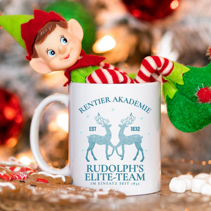 Lustige Weihnachtstasse mit Rentier-Motiv „Rentier Akademie – Rudolph’s Elite-Team“ in winterlichem Design. Geschenkidee für Weihnachten, ideal für Familie, Freunde, Kollegen. Perfekt für Kaffee, Tee, Glühwein oder heiße Schokolade. Spülmaschinenfest, mikrowellengeeignet & beidseitig bedruckt. Winterbecher mit Schneeflocken & Rentieren – ideal als Wichtelgeschenk, Weihnachtsgeschenk, Nikolausüberraschung oder fürs Büro. Hochwertiger Druck, nachhaltige Produktion in Deutschland. Weihnachtstasse