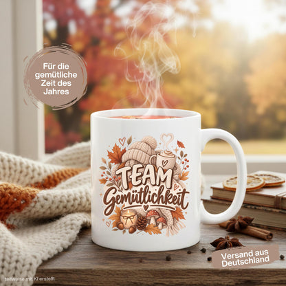 Herbst Tasse mit Spruch „Team Gemütlichkeit“ als gemütliches Herbst Geschenk, Me Time Geschenk und Geschenk für beste Freundin. Weiße Keramiktasse 330 ml beidseitig bedruckt mit herbstlichem Cozy-Season-Motiv aus warmer Tasse, Strickmütze, Kuscheldecke, Kerze, Pilzen, Tannenzapfen, Eicheln und Herbstblättern. Herbsttasse für Herbstzeit und gemütliche Kaffee-, Tee- oder Kakaomomente, ideal als Geschenk für Kaffeeliebhaber, Freundin, Mama, Schwester und echte Herbstfans.