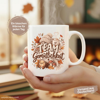 Herbst Tasse mit Spruch „Team Gemütlichkeit“ als gemütliches Herbst Geschenk, Me Time Geschenk und Geschenk für beste Freundin. Weiße Keramiktasse 330 ml beidseitig bedruckt mit herbstlichem Cozy-Season-Motiv aus warmer Tasse, Strickmütze, Kuscheldecke, Kerze, Pilzen, Tannenzapfen, Eicheln und Herbstblättern. Herbsttasse für Herbstzeit und gemütliche Kaffee-, Tee- oder Kakaomomente, ideal als Geschenk für Kaffeeliebhaber, Freundin, Mama, Schwester und echte Herbstfans.