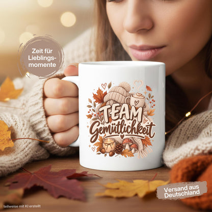 Herbst Tasse mit Spruch „Team Gemütlichkeit“ als gemütliches Herbst Geschenk, Me Time Geschenk und Geschenk für beste Freundin. Weiße Keramiktasse 330 ml beidseitig bedruckt mit herbstlichem Cozy-Season-Motiv aus warmer Tasse, Strickmütze, Kuscheldecke, Kerze, Pilzen, Tannenzapfen, Eicheln und Herbstblättern. Herbsttasse für Herbstzeit und gemütliche Kaffee-, Tee- oder Kakaomomente, ideal als Geschenk für Kaffeeliebhaber, Freundin, Mama, Schwester und echte Herbstfans.