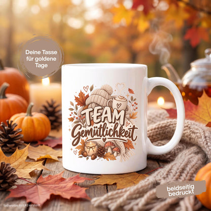 Herbst Tasse mit Spruch „Team Gemütlichkeit“ als gemütliches Herbst Geschenk, Me Time Geschenk und Geschenk für beste Freundin. Weiße Keramiktasse 330 ml beidseitig bedruckt mit herbstlichem Cozy-Season-Motiv aus warmer Tasse, Strickmütze, Kuscheldecke, Kerze, Pilzen, Tannenzapfen, Eicheln und Herbstblättern. Herbsttasse für Herbstzeit und gemütliche Kaffee-, Tee- oder Kakaomomente, ideal als Geschenk für Kaffeeliebhaber, Freundin, Mama, Schwester und echte Herbstfans.
