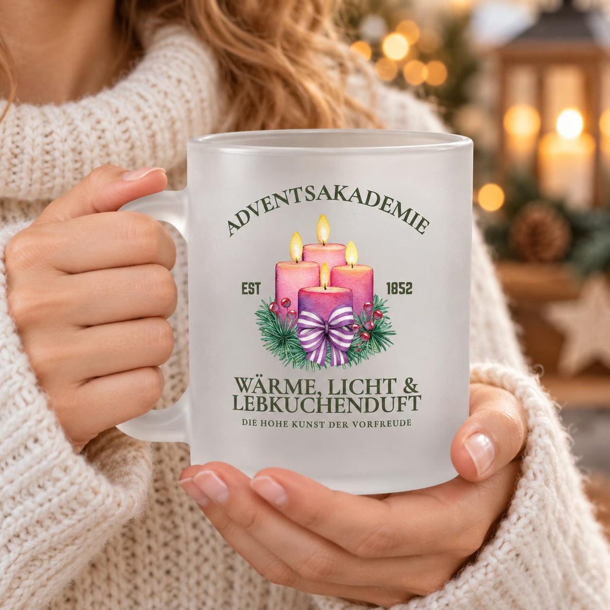 Adventsakademie-Weihnachtstasse aus satiniertem Glas, in den Händen gehalten. Auf dem Becher sind vier rosa Adventskerzen mit Flammen, Tannengrün und einer gestreiften Schleife zu sehen. Der Schriftzug „Wärme, Licht & Lebkuchenduft“ ergänzt das weihnachtliche Motiv. Die Glastasse mit Henkel und ca. 300 ml Fassungsvermögen ist beidseitig bedruckt. Ein Weihnachtsgeschenk oder Wichtelgeschenk für Menschen, die die Adventszeit lieben; als Kaffeetasse, Teetasse oder Becher für heißen Kakao.