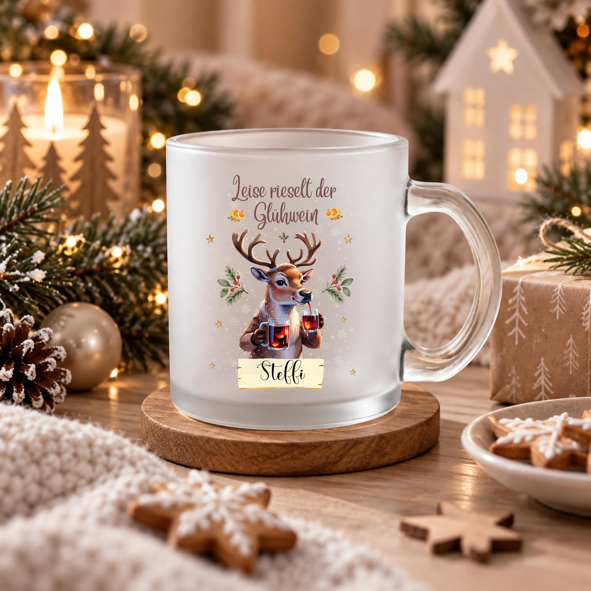 Personalisierte Glühweintasse mit Namen und dem Spruch „Leise rieselt der Glühwein" zeigt diese transparente, satinierte Glastasse mit einem Rentier, das zwei Gläser Glühwein hält, umgeben von Tannengrün und Sternen. Diese Tasse personalisiert wird mit dem Wunschnamen auf einem kleinen Schild bedruckt. Diese Weihnachtstasse mit Namen eignet sich als Weihnachtsgeschenk-Tasse für Mama, Papa oder die ganze Familie und macht aus jeder Glühweintasse ein persönliches Unikat für die Adventszeit.