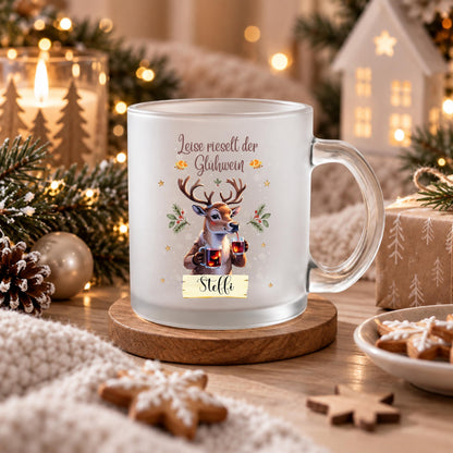 Personalisierte Glühweintasse mit Namen und dem Spruch „Leise rieselt der Glühwein" zeigt diese transparente, satinierte Glastasse mit einem Rentier, das zwei Gläser Glühwein hält, umgeben von Tannengrün und Sternen. Diese Tasse personalisiert wird mit dem Wunschnamen auf einem kleinen Schild bedruckt. Diese Weihnachtstasse mit Namen eignet sich als Weihnachtsgeschenk-Tasse für Mama, Papa oder die ganze Familie und macht aus jeder Glühweintasse ein persönliches Unikat für die Adventszeit.
