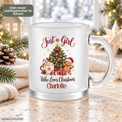 Personalisierte Weihnachtstasse aus satiniertem, transparentem Glas mit dem Beispielnamen Charlotte im weihnachtlichen Arrangement. Der Aufdruck „Just a Girl Who Loves Christmas“ zeigt einen geschmückten Tannenbaum, Kakao mit Zuckerstange, Lebkuchenmann und Geschenke. Sichtbar sind der klare Glasgriff und der Glasboden; Tannenzweige, Strickdecke und Lichter rahmen die Tasse ein. Die beidseitig bedruckte 300-ml-Glastasse mit Wunschname eignet sich als Weihnachtsgeschenk für Freundin, Schwester oder Kollegin.