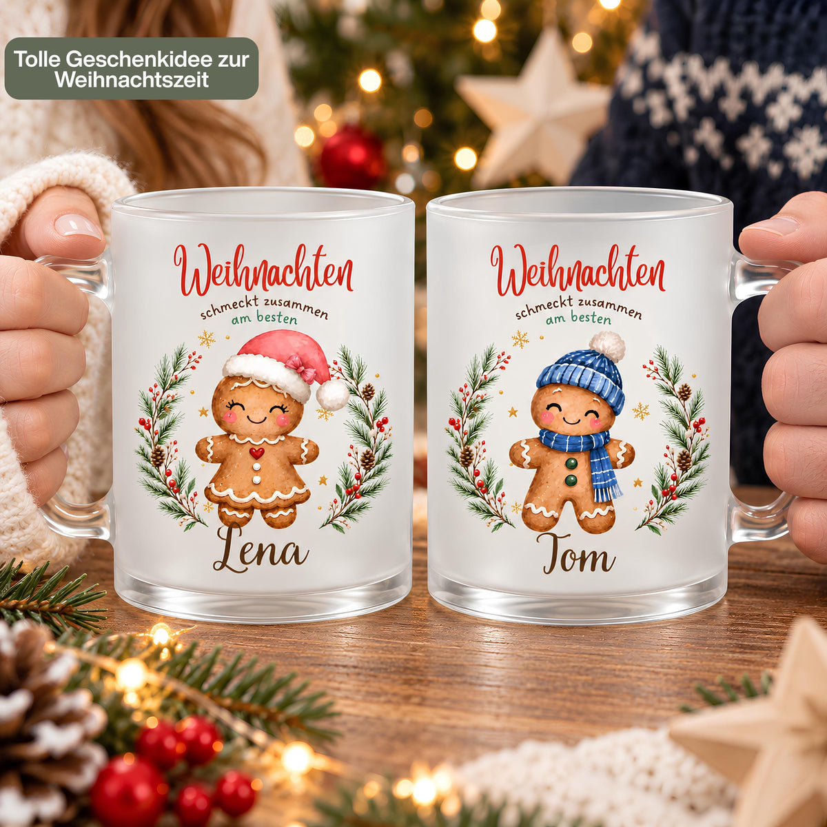 Zwei personalisierte Weihnachtstassen werden nebeneinander in Händen gehalten. Die Nahaufnahme zeigt die Lebkuchenfiguren, Wunschbeschriftungen und transparenten Glasgriffe. Die Lebkuchenmotive sind von einem Tannenkranz mit Zapfen, Beeren und goldenen Sternen umrahmt und tragen „Weihnachten schmeckt zusammen am besten“. Die satinierte 300-ml-Glastasse wird beidseitig mit Wunschname bedruckt. Persönliches Weihnachtsgeschenk für Familie, Freunde oder Kollegen, auch zu Nikolaus oder zum Wichteln. Im Advent.