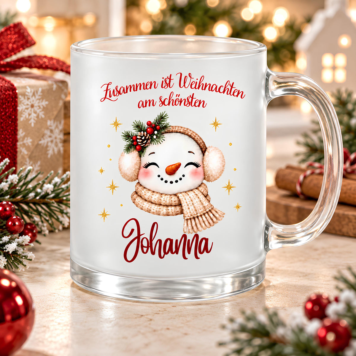 Personalisierte Weihnachtstasse mit Namen Johanna aus satiniertem Glas. Der Schneemann mit Karottennase und rosa Wangen trägt beige Ohrenschützer und einen Strickschal, geschmückt mit Tannengrün, Beeren und Zapfen. Goldene Sterne umrahmen das Motiv; darüber steht „Zusammen ist Weihnachten am schönsten“, darunter Johanna in roter Schreibschrift. Der transparente Henkel liegt rechts. Auf dem hellen Holztisch bilden Christbaumkugeln, Geschenke, Plätzchen und warme Lichter eine festliche Weihnachtskulisse.