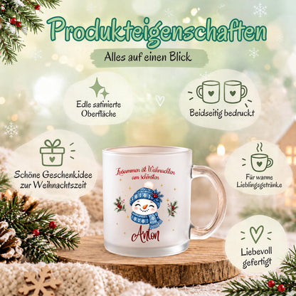 Infografik „Produkteigenschaften – Alles auf einen Blick“ zur personalisierten Schneemann-Glastasse. In der Mitte steht eine satinierte Weihnachtstasse mit Namen Anton, blauem Schneemann-Motiv und transparentem Henkel auf einer Holzscheibe. Symbole beschreiben die edle satinierte Oberfläche, den beidseitigen Druck, die Geschenkidee zur Weihnachtszeit, die Nutzung für warme Lieblingsgetränke und die liebevolle Fertigung. Tannenzweige, Zapfen, Strickstoff und warme Lichter bilden den Hintergrund.