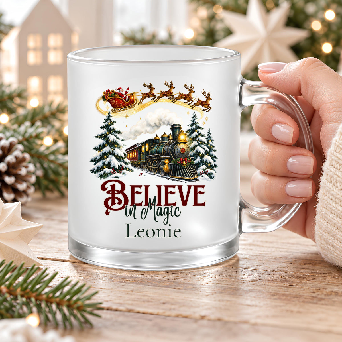 Personalisierte Weihnachtstasse mit Namen Leonie, am transparenten Glashenkel gehalten. Believe in Magic Schriftzug, Weihnachtsbahn und Weihnachtsmann auf satiniertem Glas. Die Tasse mit Wunschname fasst ca. 300 ml und ist beidseitig bedruckt. Weihnachtsbecher für Kaffee, Tee, Kakao oder Glühwein, als Weihnachtsgeschenk für Mama, Oma, Schwester oder die beste Freundin. Individuelle Kaffeetasse als Nikolausgeschenk und Wichtelgeschenk für die Adventszeit, Weihnachten und gemütliche Wintertage.