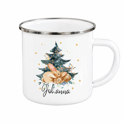 Personalisierte Weihnachtstasse für Kinder aus weißer Emaille mit silberfarbenem Rand und weißem Henkel. Das Hasenmotiv zeigt zwei braune Hasen unter einem geschmückten Weihnachtsbaum. Unter der winterlichen Illustration steht ein Beispielname; die Kindertasse wird mit Wunschname bedruckt. Persönlicher Weihnachtsbecher für kleine Hasenfans und eine Geschenkidee zu Weihnachten oder Nikolaus für Kinder, Enkelkinder und Patenkinder. Nahansicht von Hasenmotiv und Namensdruck.