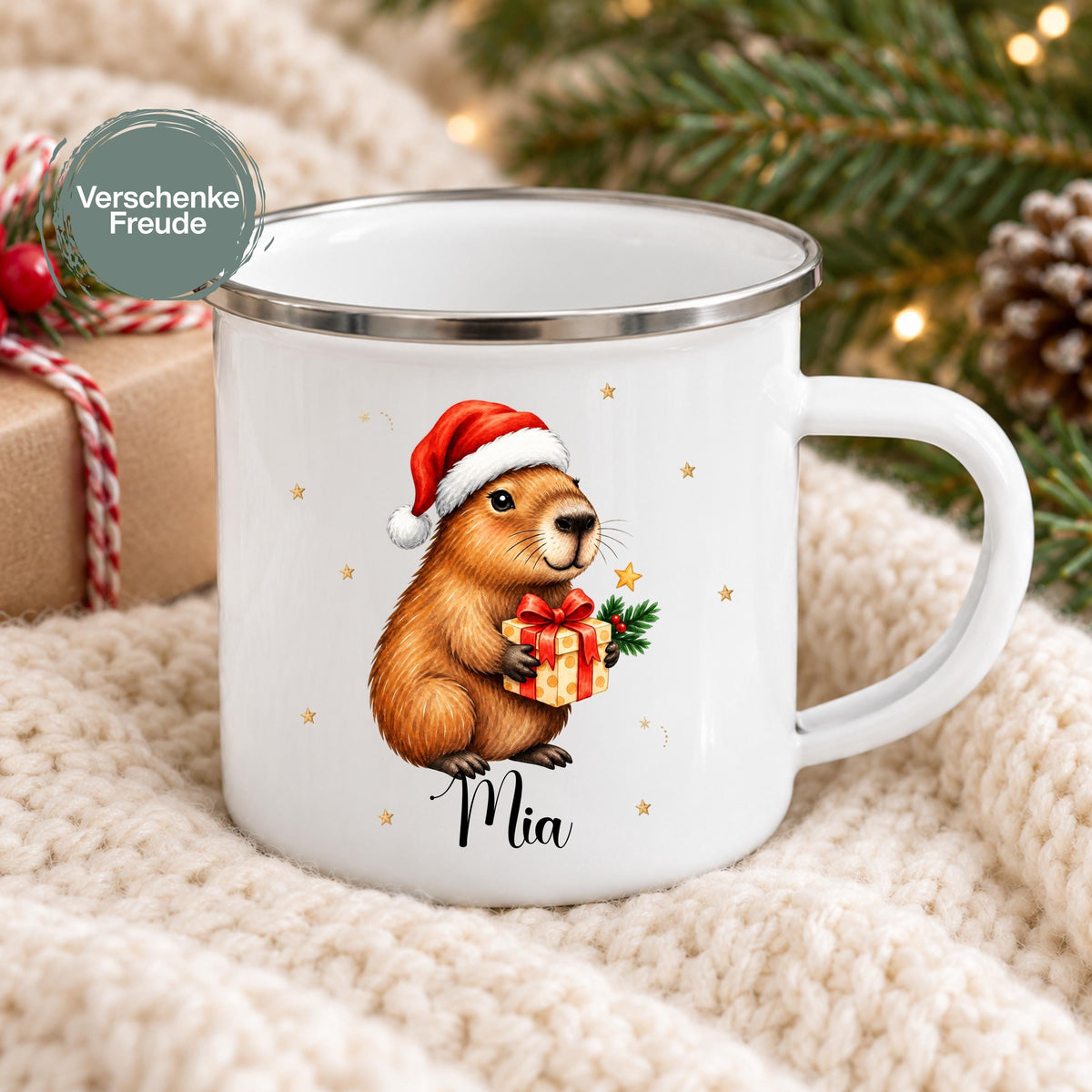 Personalisierte Weihnachtstasse für Kinder aus weißer Emaille mit silberfarbenem Rand und weißem Henkel. Das Weihnachtsmotiv zeigt ein Capybara mit roter Weihnachtsmütze und einem Geschenk mit roter Schleife. Unter dem Tiermotiv steht ein Beispielname; die Kindertasse wird mit Wunschname bedruckt. Persönlicher Weihnachtsbecher für Capybara-Fans und eine Geschenkidee zu Weihnachten oder Nikolaus für Kinder, Enkelkinder und Patenkinder. Frontansicht mit dem Beispielnamen Mia.