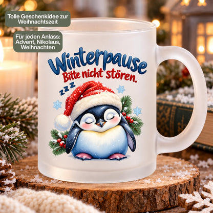 Diese Tasse Weihnachten zeigt einen schlafenden Pinguin mit Nikolausmütze und den Spruch 'Winterpause: Bitte nicht stören', umgeben von Tannenzweigen und Schneeflocken. Als Weihnachtsbecher aus satiniertem Glas mit 300 ml Fassungsvermögen eignet sie sich perfekt als Weihnachtsgeschenk, Wichtelgeschenk oder Nikolaus Tasse. Eine humorvolle Kaffeetasse Weihnachten für Kaffee, Tee, Kakao und Glühwein, ideal als Winter Tasse für alle, die den Winter am liebsten verschlafen würden.