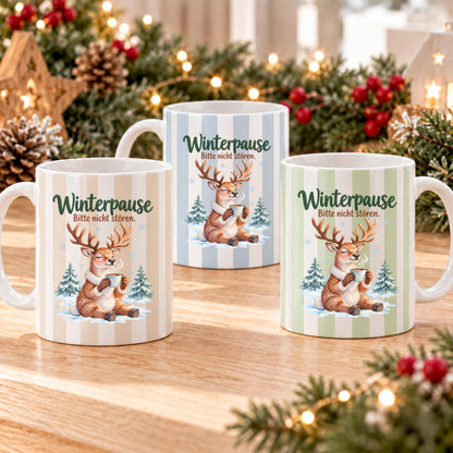 Weihnachtstasse mit dem Spruch „Winterpause, Bitte nicht stören" zeigt drei Varianten dieser Keramiktasse Weihnachten in Beige, Grün und Blau mit zartem Streifendesign. Auf jeder Kaffeetasse Weihnachten liegt ein schläfriges Rentier im Schnee zwischen kleinen Tannen und hält eine dampfende Tasse in den Pfoten. Diese Winter Tasse Geschenk eignet sich als Wichtelgeschenk Tasse, Weihnachtsgeschenk Tasse oder Weihnachtsbecher Geschenk und ist rundherum mit dem winterlichen Motiv bedruckt.