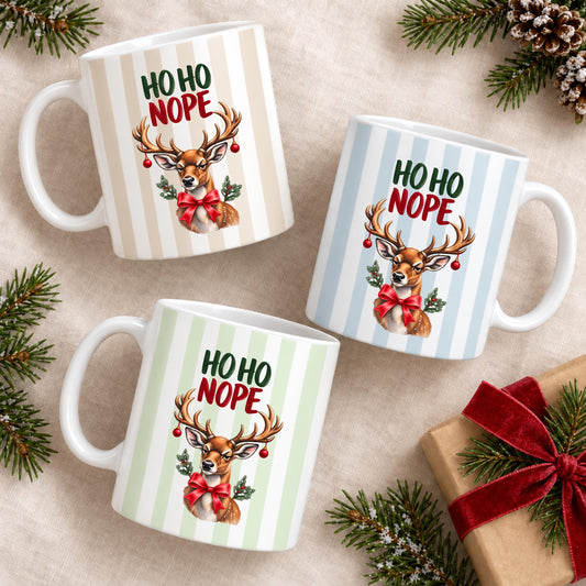 Lustige Weihnachtstasse mit Anti Weihnachten Spruch „Ho Ho Nope" zeigt diese Keramiktasse Weihnachten in drei Farben, jeweils mit feinem Streifendesign. Auf jeder Kaffeetasse Weihnachten blickt ein skeptisches Rentier mit rotem Schleifchen und Christbaumkugeln im Geweih. Diese lustige Weihnachtstasse mit Anti Weihnachten Sprüche eignet sich als Wichtelgeschenk Tasse, Weihnachtsgeschenk Tasse oder Weihnachtsbecher Geschenk für alle mit Humor zur Adventszeit. Anti Weihnachten Sprüche