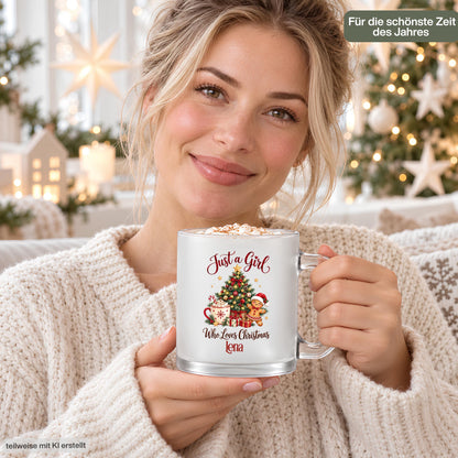 Eine Frau im hellen Strickpullover hält die personalisierte Weihnachtstasse mit dem Beispielnamen Lena und Kakao mit Sahne. Die satinierte Glastasse zeigt „Just a Girl Who Loves Christmas“ mit Tannenbaum, Lebkuchenmann, Geschenken und Zuckerstange. Im Hintergrund leuchten Weihnachtsbaum, Sterne und ein Dekohäuschen; oben steht „Für die schönste Zeit des Jahres“. Der 300-ml-Weihnachtsbecher mit Wunschname und transparentem Henkel ist eine Geschenkidee für Freundin, Schwester oder Kollegin zu Weihnachten.